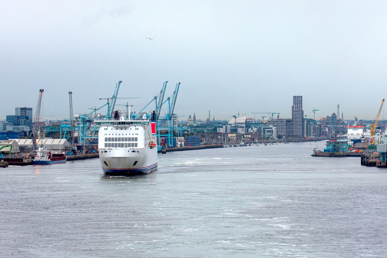 Eine Fähre läuft in den Dublin Port ein, dahinter Hafenkräne und die Skyline von Dublin